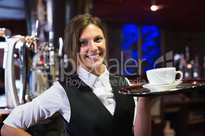 Happy barmaid holding tray with coffee