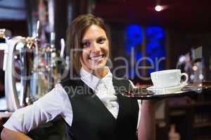 Happy barmaid holding tray with coffee