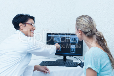 Dentist showing woman her mouth x-ray on computer