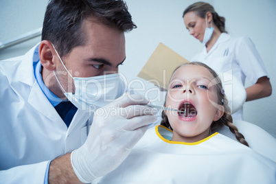 Male dentist examining girls teeth