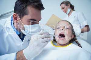 Male dentist examining girls teeth