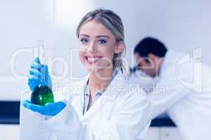 Science student holding green chemical in beaker