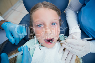 Dentist with assistant examining girls teeth