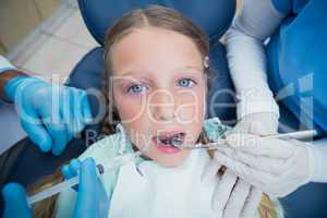 Dentist with assistant examining girls teeth