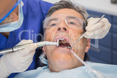 Dentist examining a patient with tools