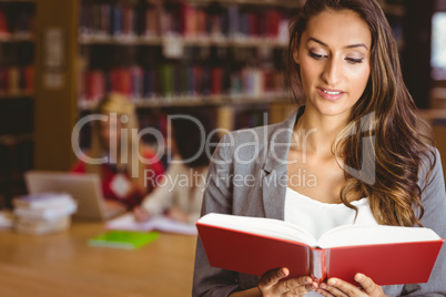Pretty brunette student standing and reading book