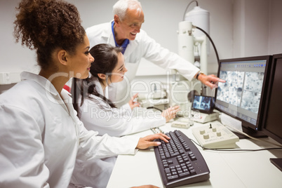 Science students looking at microscopic image on computer with l