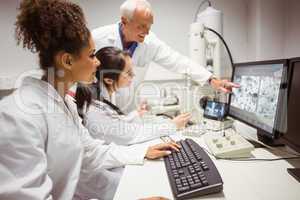 Science students looking at microscopic image on computer with l