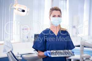 Dentist in mask holding tray of tools