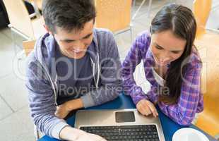 Young students doing assignment on laptop together