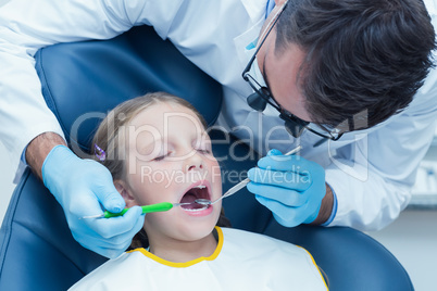 Male dentist examining girls teeth