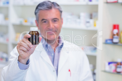 Pharmacist showing a drug bottle to camera