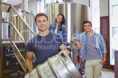 Young man holding keg with these colleagues behind him