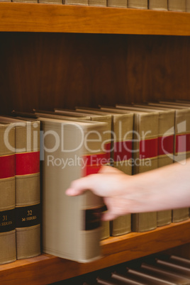 Hand taking a book from bookshelf