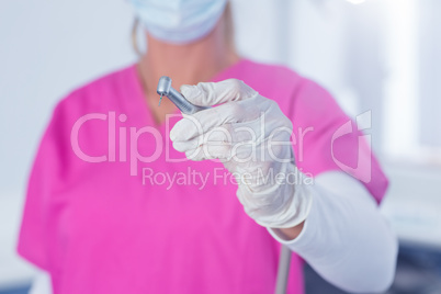 Dentist in surgical mask and scrubs holding tool