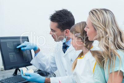 Dentist and assistant showing little girl her mouth x-ray