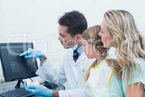 Dentist and assistant showing little girl her mouth x-ray