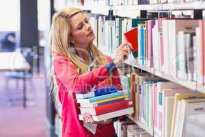 Mature student in library picking book
