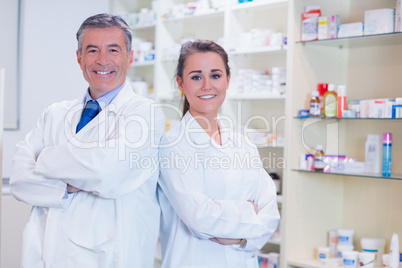 Pharmacist with his trainee standing with arms crossed