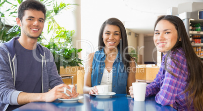 Young students smiling at camera in cafe