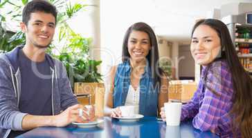 Young students smiling at camera in cafe