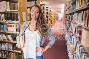 Pretty student holding books in library