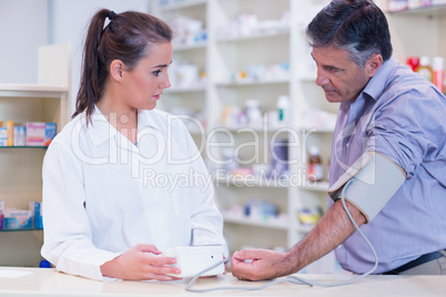 Young trainee taking blood pressure of his customer