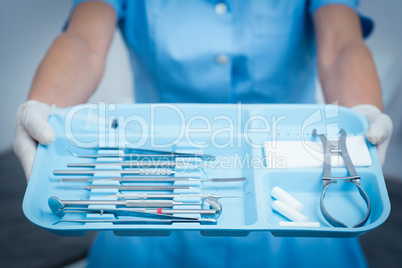 Mid section of dentist holding tray of tools Mid section of dentist holding tray of tools
