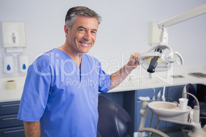 Portrait of a friendly dentist holding light