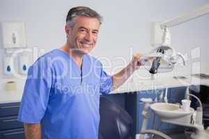 Portrait of a friendly dentist holding light