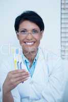 Smiling female dentist holding toothbrushes