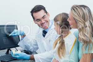 Dentist with assistant showing little girl her mouth x-ray