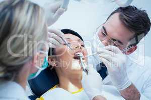 Dentist with assistant examining womans teeth