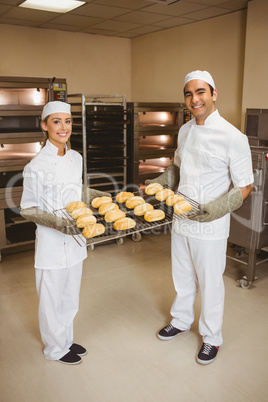 Team of bakers holding rack of rolls