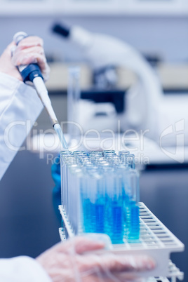 Science student using pipette in the lab to fill test tubes