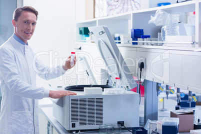 Smiling chemist holding a test tube looking at camera