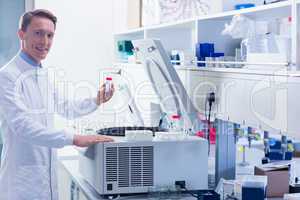 Smiling chemist holding a test tube looking at camera