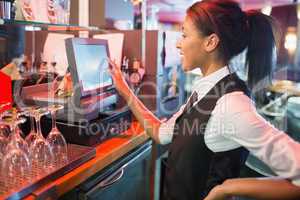 Pretty barmaid using touchscreen till