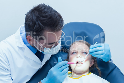 Male dentist examining girls teeth