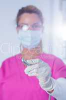 Dentist in surgical mask and scrubs holding tool