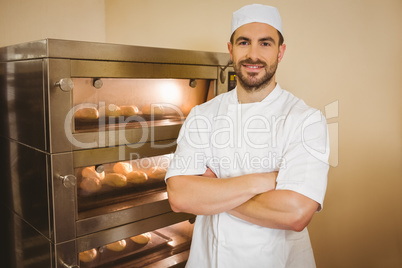 Baker smiling at camera beside oven