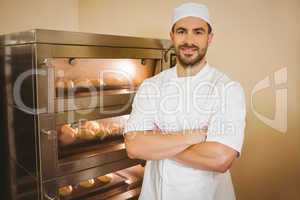 Baker smiling at camera beside oven