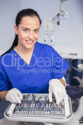 Smiling dentist picking up a tool on the tray