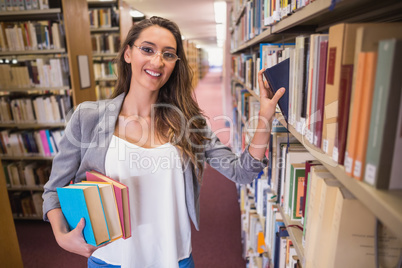 Pretty student picking out a book in library