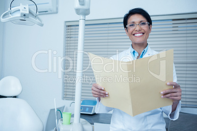 Smiling female dentist reading reports