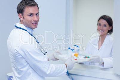 Doctor giving tray with blood sample to his colleague