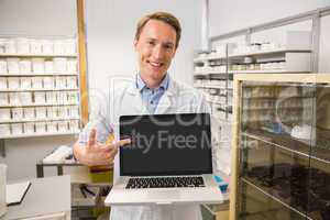 Happy pharmacist showing laptop screen