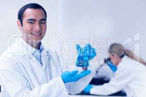 Science student holding blue chemical in beaker