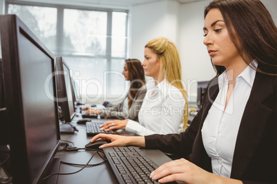 Three focused women working in computer room