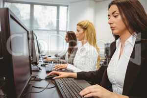 Three focused women working in computer room